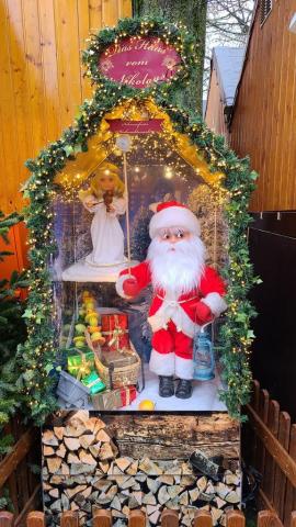 Die Nikolaus-Puppe steht in einem kleinen Häuschen und klopft mit einem Stab an die Scheibe
