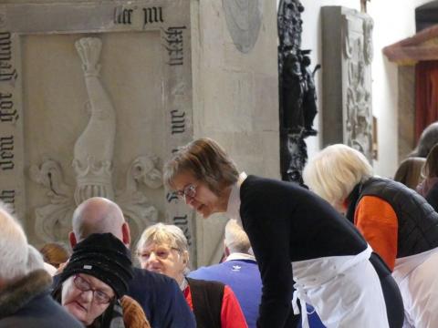 Regionalbischöfin Gisela Bornowski bedient Gäste am Tisch in der Vesperkirche