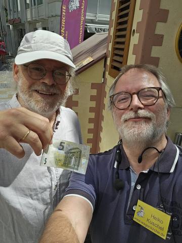 Lorenz Hummel und Heiko Kuschel stehen vor der Wagenkirche und halten einen 5-Euro-Schein ins Bild