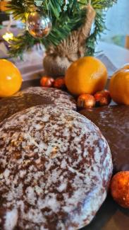 Lebkuchen, Mandarinen und kleine Schokokügelchen auf einem Teller. Im Hintergrund ein kleiner Tannenbaum.