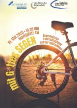 Das Hinterrad eines Fahrrads. Text: "Mit G*ttes Segen - ökumenische Fahrradsegnung bei der Kidical Mass"